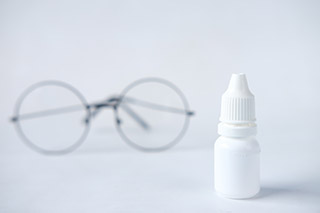 Eye drop medicine in front of reading glasses.